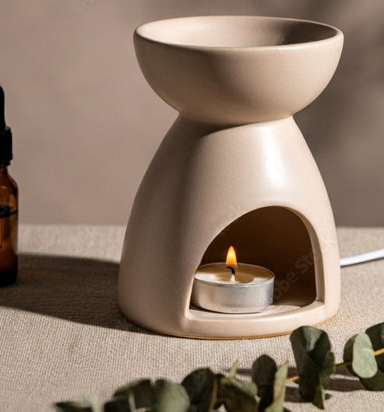 Diffuseur artisanal sur une console en bois, entouré de plantes et d’objets décoratifs naturels.