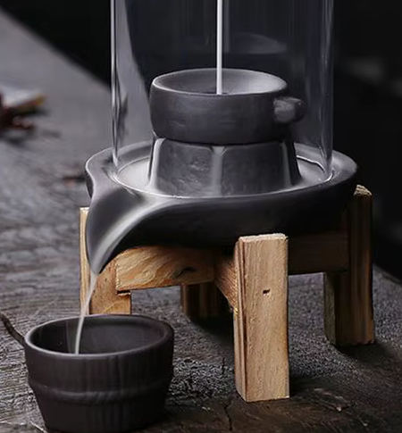 Fumée en cascade s’écoulant sur un porte-encens sculpté, posé sur une console décorative.