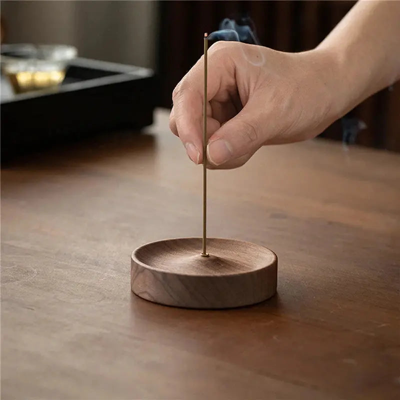 Porte-encens bâtons en noyer rond avec un encens allumé diffusant de la fumée.