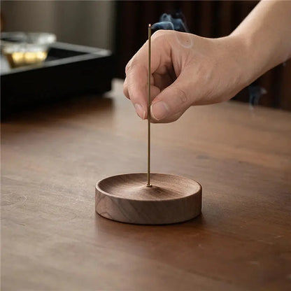Porte-encens bâtons en noyer rond avec un encens allumé diffusant de la fumée.